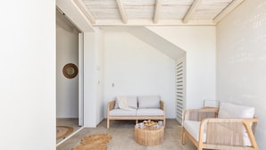 A modern living room with a light-colored sofa, a wicker chair, and a round coffee table. - 2940 Palma Residence- Appartamento Notos by Barbarhouse (Melendugno)