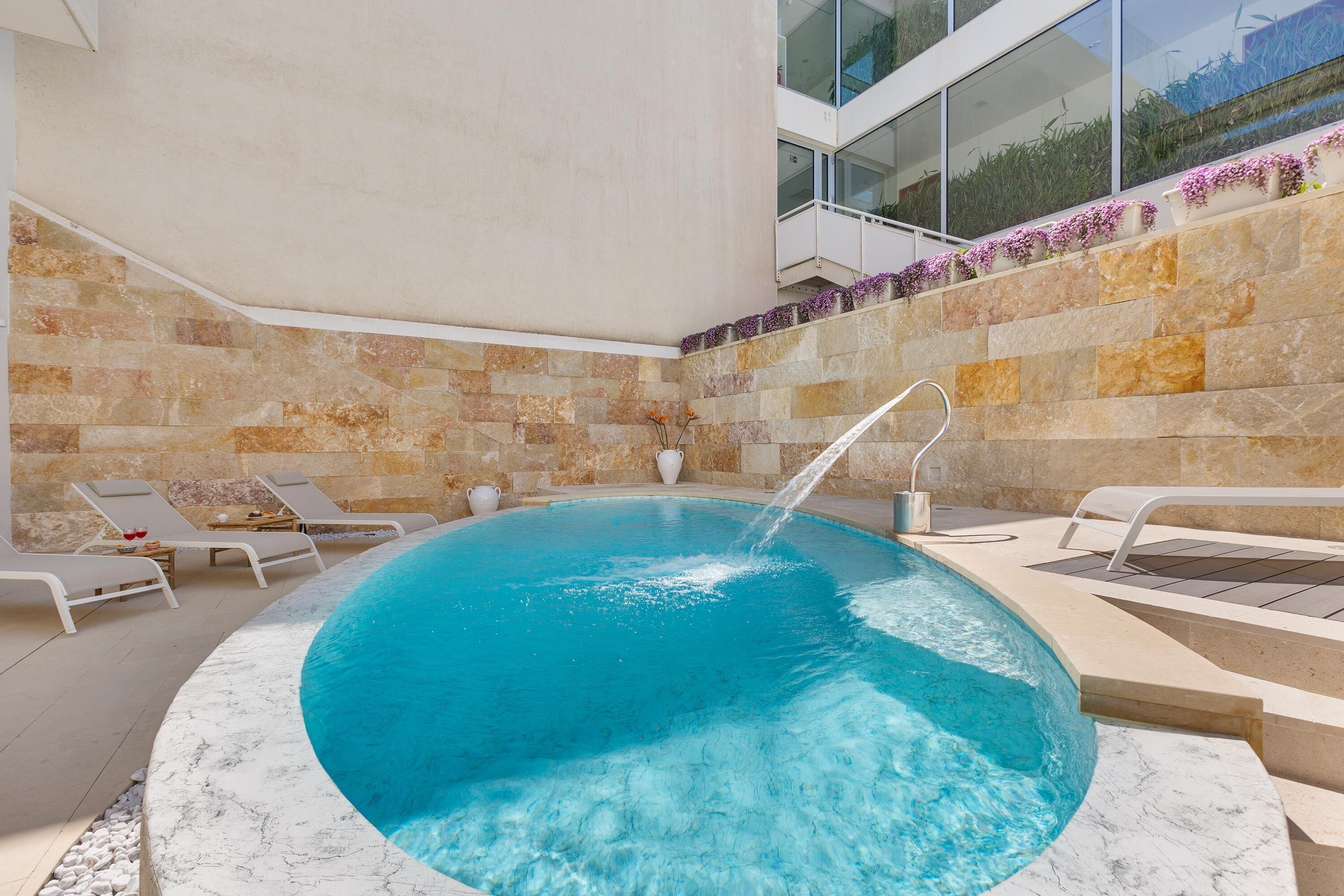 A swimming pool with a stone wall and a glass balustrade.