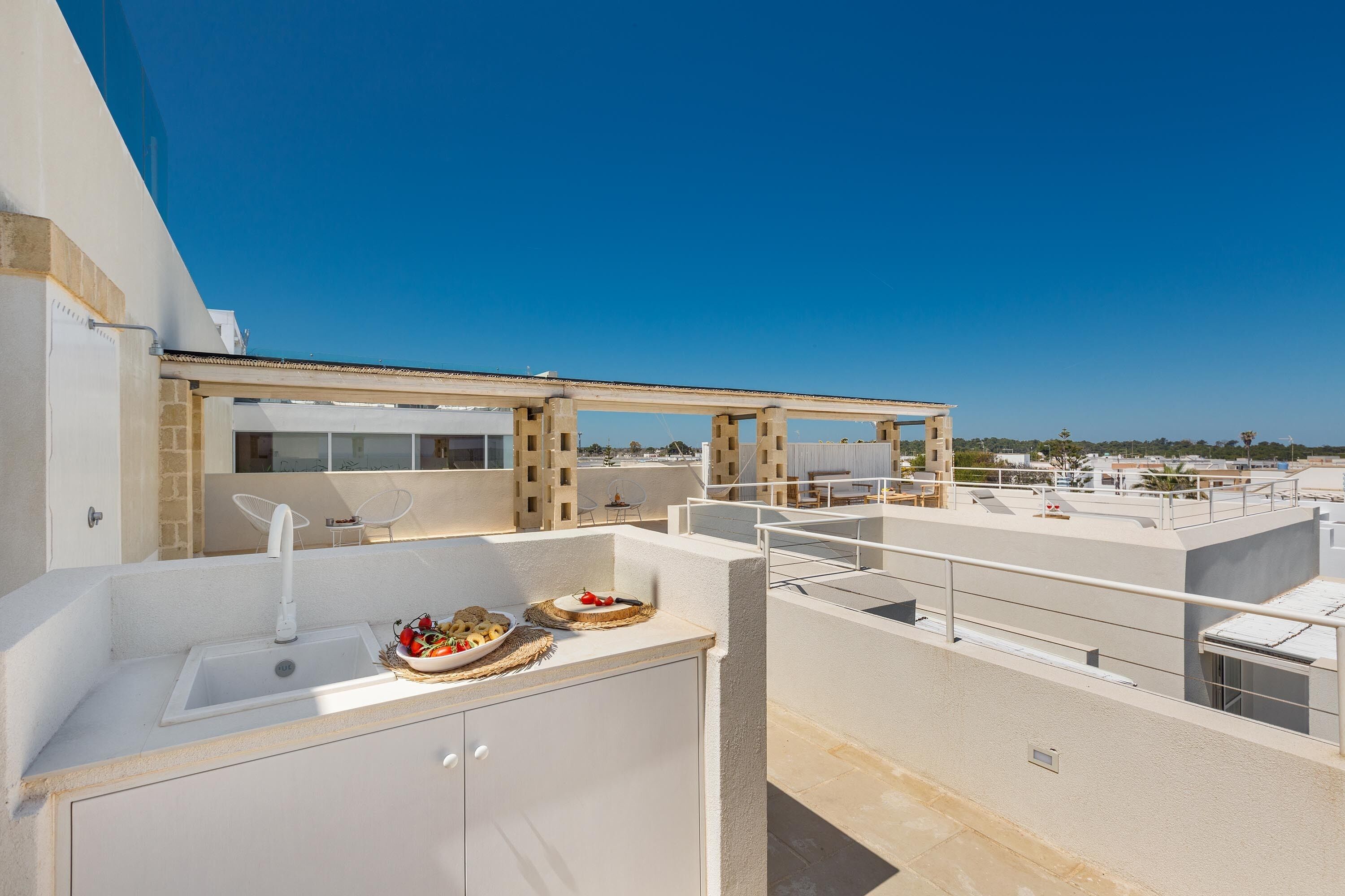 A rooftop terrace with a sink and dining area, offering a view of the cityscape.