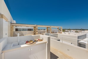 Eine Dachterrasse mit Spüle und Essbereich, mit Blick auf die Stadt.