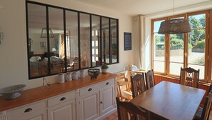 Un comedor con una mesa y sillas de madera, un espejo grande sobre la encimera y una ventana con vistas a la vegetación.