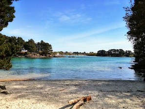 A beach with clear water, trees, and a small building in the distance. - Family holidays near the seaside, in a comfortable farmhouse with swimming pool (Concarneau)