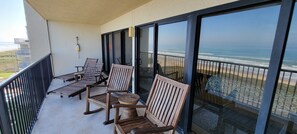 Een balkon met houten meubels en uitzicht op het strand.