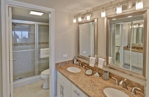 A bathroom with a double sink, a large mirror, and a shower enclosure. - Spi Fun And Sun 2 Bedroom Condo by RedAwning (South Padre Island)