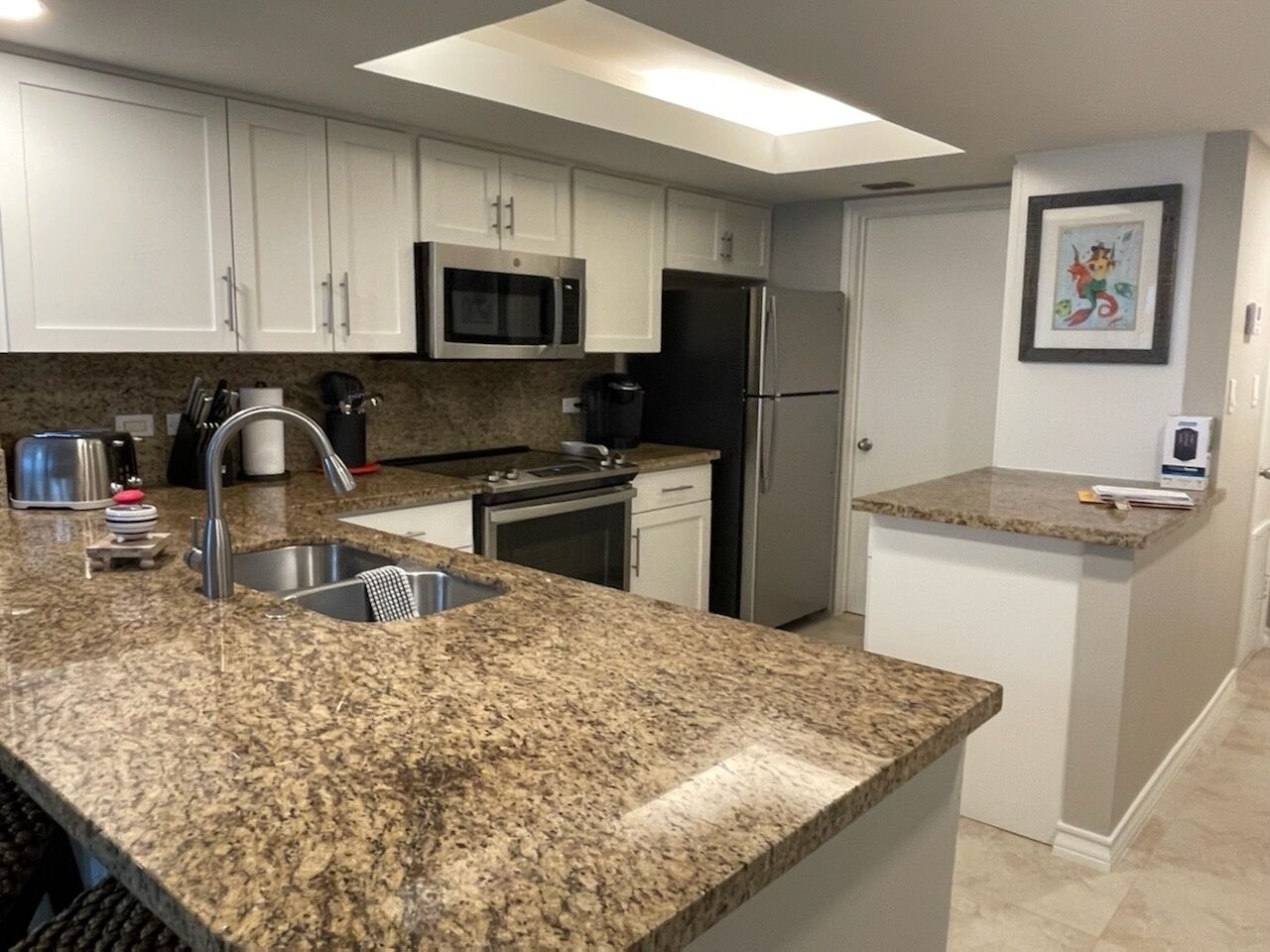 A modern kitchen with granite countertops, stainless steel appliances, and white cabinetry.