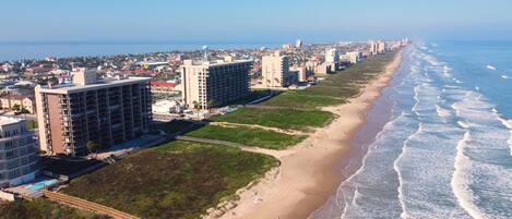 Un paisaje urbano costero con una playa, incluyendo edificios altos y una playa de arena.