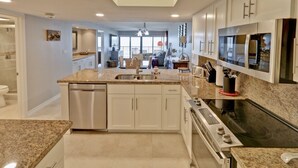 Een moderne keuken met granieten werkbladen, roestvrijstalen apparatuur en een centraal kookeiland.
