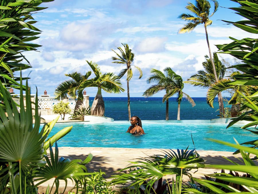 Zona de piscina con palmeras y vista al océano.