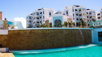 Um hotel com piscina, várias varandas e uma parede de pedra.
