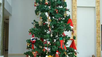 A Christmas tree in a lobby with a stone wall and a sofa in the background.