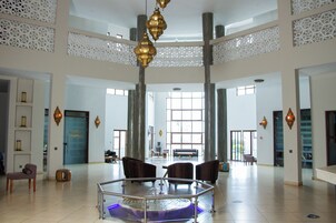 Un vestíbulo espacioso con una zona de estar central, techos altos y lámparas decorativas.
