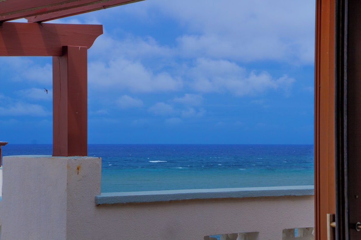 A balcony with a view of the ocean and a clear sky.