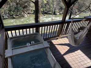 A wooden deck with a hot tub and hammock overlooking a river. - COZY RIVER FRONT CABIN (Blue Ridge)