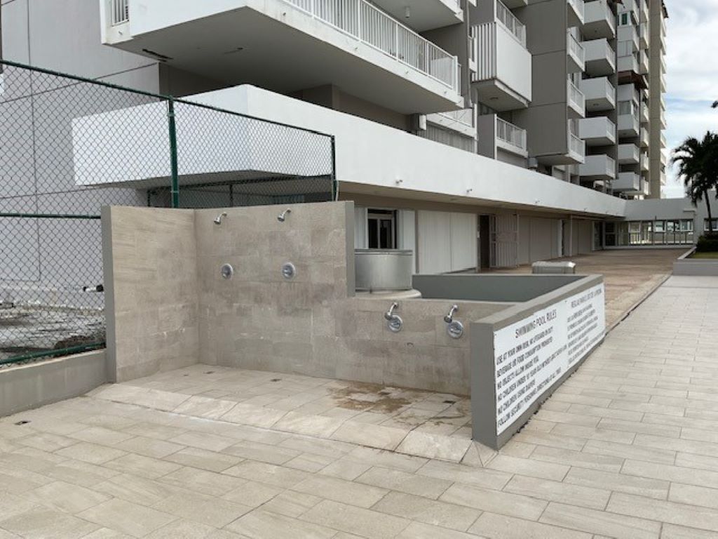 Ein modernes Gebäude mit Betonfassade, mehreren Balkonen und einer Schautafel.