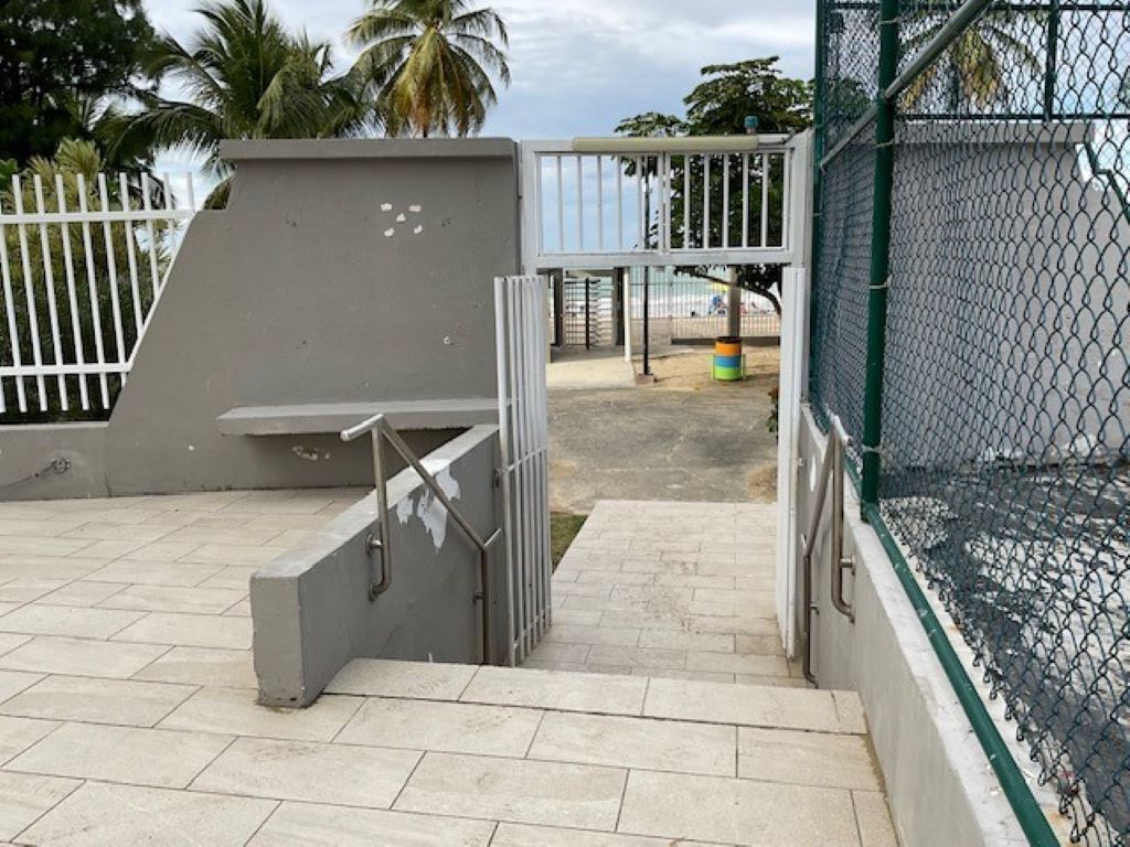 A gated outdoor area with a concrete ramp leading to a metal gate.