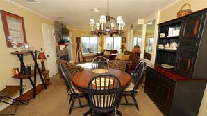 A dining area with a round table and chairs, a chandelier, and a cabinet with dishes.