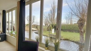 A room with large windows overlooking a pond and garden. - Pura Vida del Rio : Enjoy life ! (Oud Ade)