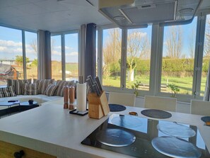 A modern kitchen with a large island, a dining area, and a view of the countryside. - Pura Vida del Rio : Enjoy life ! (Oud Ade)