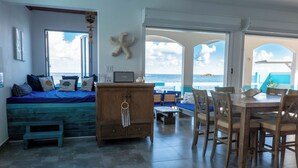 Una habitación con vistas al mar, un armario de madera, una mesa de comedor con sillas y un banco.