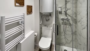 Pieni kylpyhuone, jossa on wc, suihku ja pyyheteline.