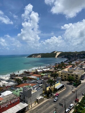 A coastal town with a beach, buildings, and a road. - Apts em Quality suites (Natal)