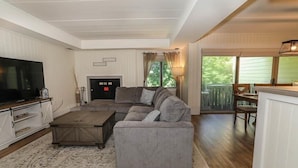 A living room with a sectional sofa, a coffee table, a flat-screen TV, and a fireplace.