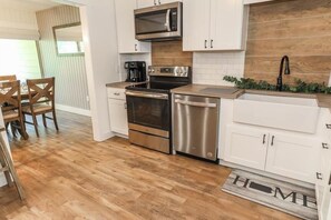 A modern kitchen with stainless steel appliances, white cabinetry, and a wooden backsplash. - Seven Springs 2 Bedroom Premium Condo, Pet Friendly! by RedAwning (Champion)