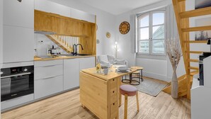 Una cocina moderna con armarios de madera, horno empotrado y comedor con mesa y sillas.