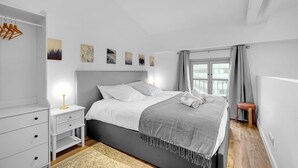 Un dormitorio moderno con una cama grande, mesitas de noche, un armario y obras de arte en la pared.