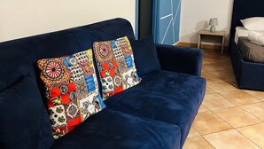 A room with a dark blue sofa, a matching blue accent wall, and a geometric-patterned door. - CARTARI APARTMENT (Palermo)