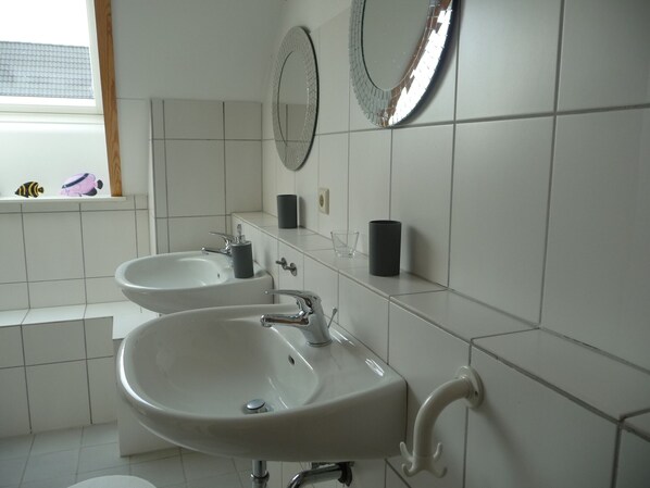Een badkamer met twee wastafels, een spiegel en een raam met speelgoed.