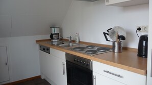 Eine kleine Küche mit Spüle, Herd und Backofen, einer Kaffeemaschine und einem Wasserkocher.