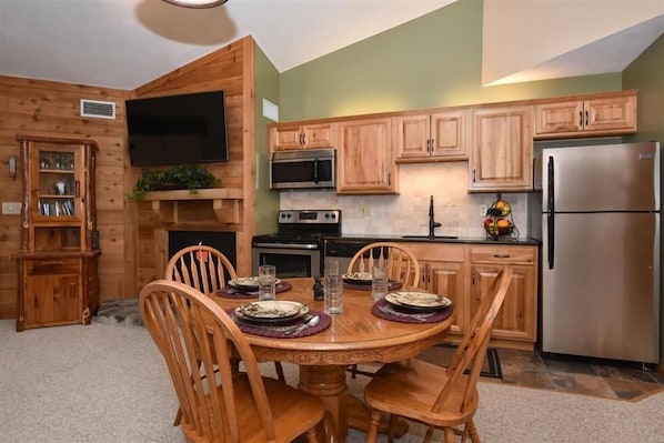 A compact kitchen with wooden cabinets, a microwave, stove, and a refrigerator.