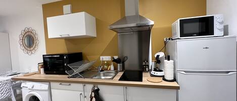 A compact kitchen with a washing machine, microwave, and a built-in oven.