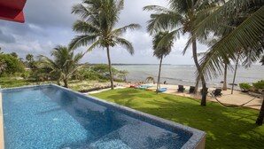 A swimming pool with a view of the ocean and palm trees. - Quiet Home on Beautiful Private Beach w/ Pool (Tulum)