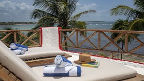 A beachside lounge with a view of the ocean, a palm tree, and a wooden railing. - Quiet Home on Beautiful Private Beach w/ Pool (Tulum)