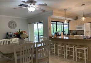 Una cocina moderna con armarios blancos, una isla grande y luminarias colgantes.