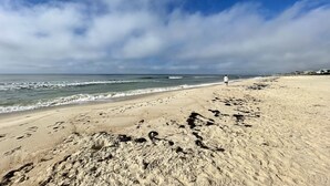 A beach with footprints leading to the water, a person walking, and houses in the distance. - Solaria: Waterfront, Heated Pool, Kayak, Fish/Golf, St George Island (Eastpoint)