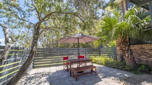 Relax in a serene outdoor space surrounded by lush greenery and a shaded patio area.