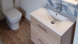 Une salle de bain comprenant des toilettes, un lavabo avec un miroir et un mur recouvert de carreaux.