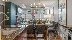 A modern kitchen with a central island, dark green accent walls, and a chandelier.