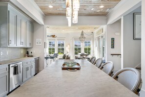 A spacious kitchen with a large island, modern cabinetry, and a dining area with wicker chairs.