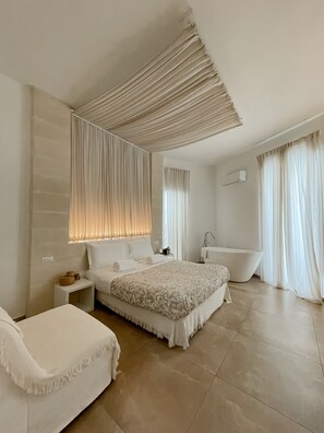 Una camera da letto moderna con un letto grande, un comodino, una vasca da bagno e una finestra con tende.