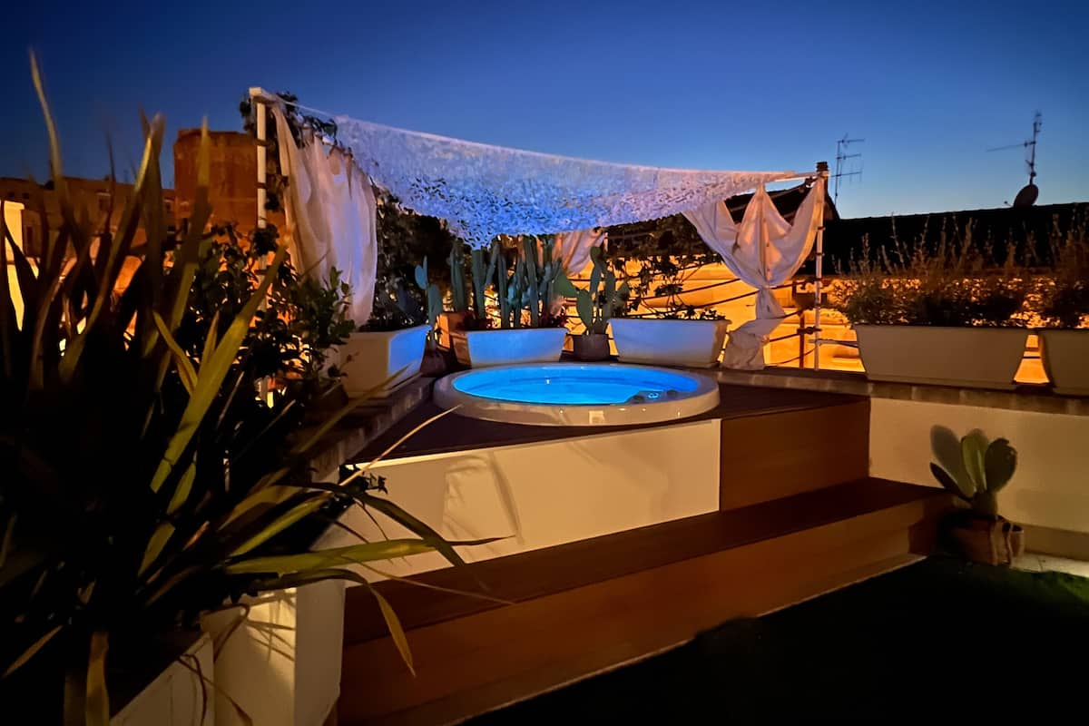 A pool area with a blue pool, surrounded by plants and a white canopy.