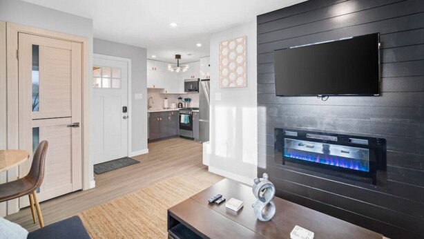 Una cocina moderna con gabinetes blancos, encimera negra y un microondas integrado.