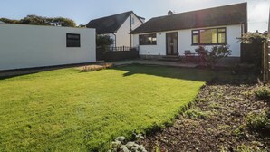 A residential property with a well-maintained lawn, a small patio area, and a white exterior wall. - Marsh Garth (Kirkby-in-Furness)