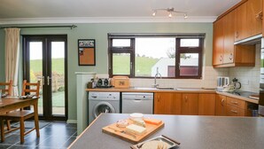 A kitchen with a large island, a washing machine, a toaster, and a window with a view of the outdoors. - Marsh Garth (Kirkby-in-Furness)