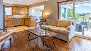 A spacious living area with a sofa, a coffee table, and a view of a balcony. - The Summit | Nature Lovers Dream! Family Friendly (Vernon)