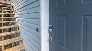 A wooden staircase leading to a dark blue door with a silver handle and a keyhole.