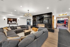 A modern living room with a sectional sofa, a fireplace, and a ski equipment rental sign.